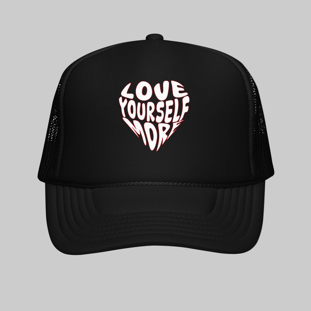 Black trucker hat with 'Love Yourself More' in a heart shape on a white background
