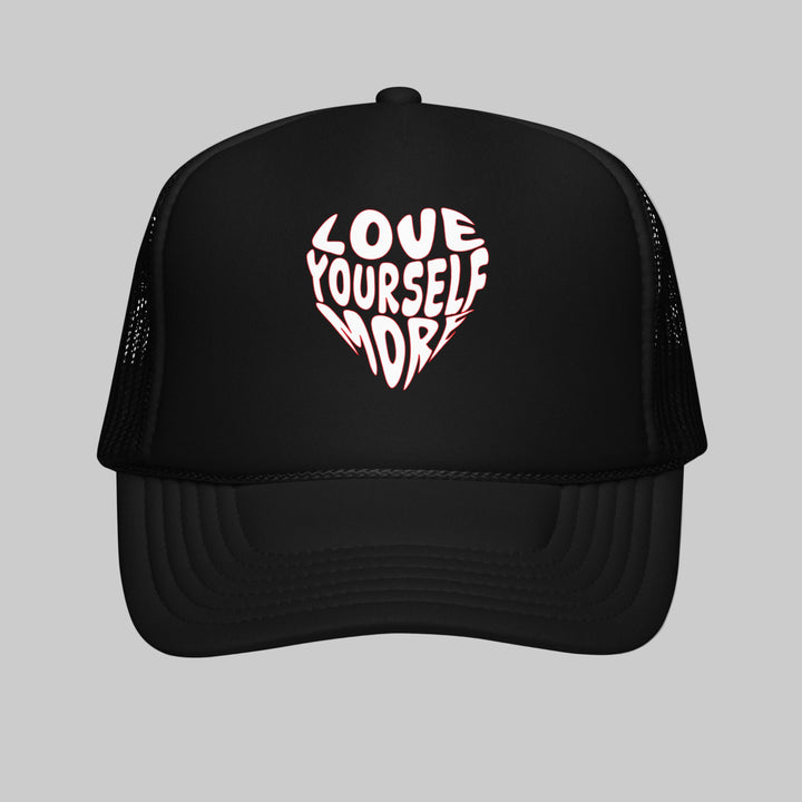 Black trucker hat with 'Love Yourself More' in a heart shape on a white background