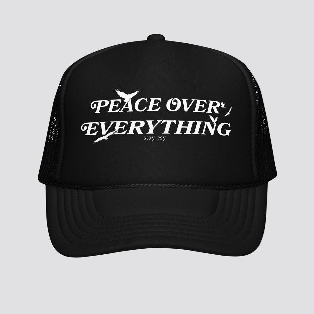 Black trucker hat with 'Peace Over Everything' text on a white background