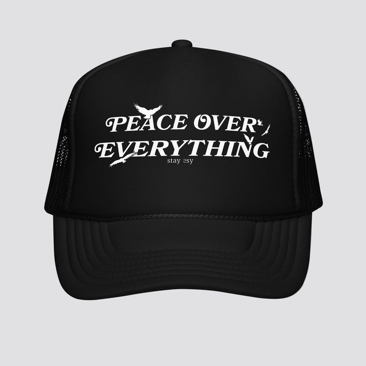 Black trucker hat with 'Peace Over Everything' text on a white background
