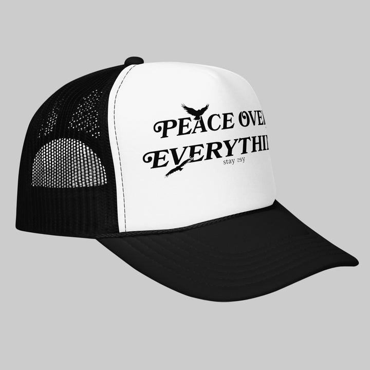Black and white trucker hat with 'Peace Over Everything' text on a white background