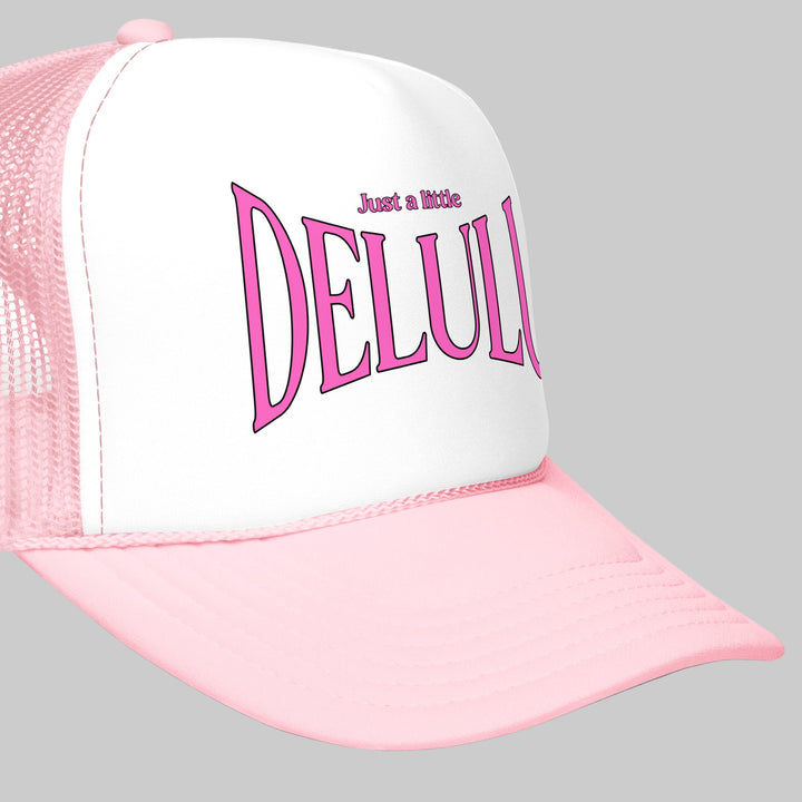 Pink and white cap with 'Just a little DELULU' text on a white background