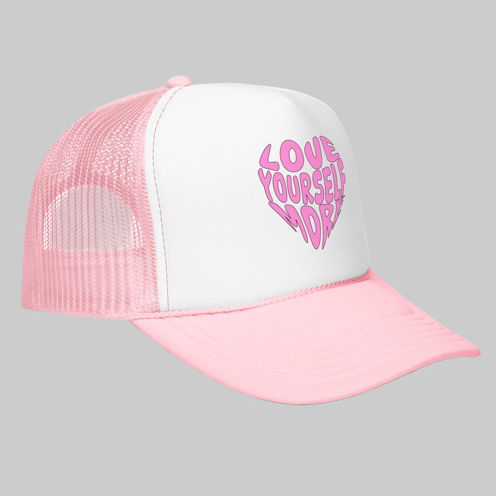 Pink and white cap with 'Love Yourself More' text on a white background