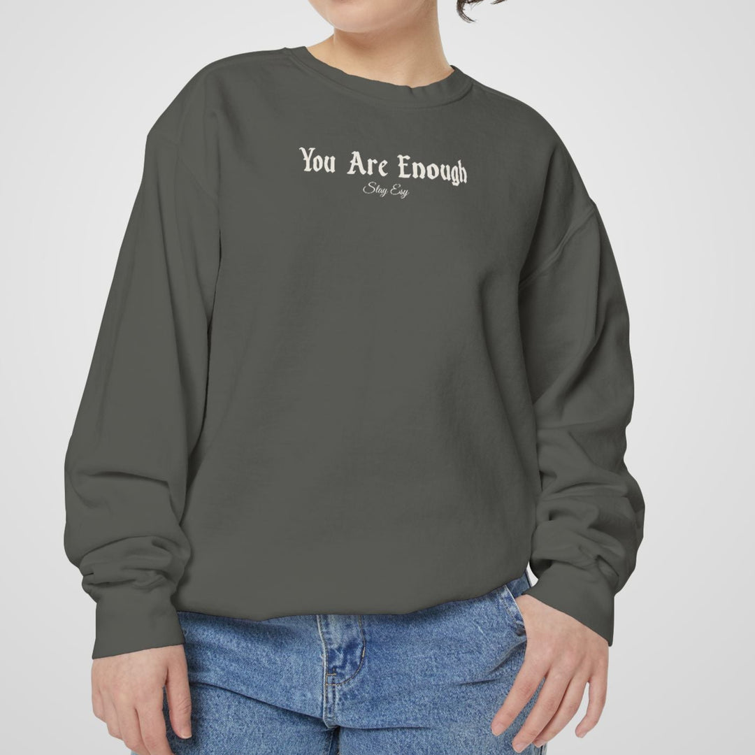 Person wearing a gray sweatshirt with 'You Are Enough' text on a plain background