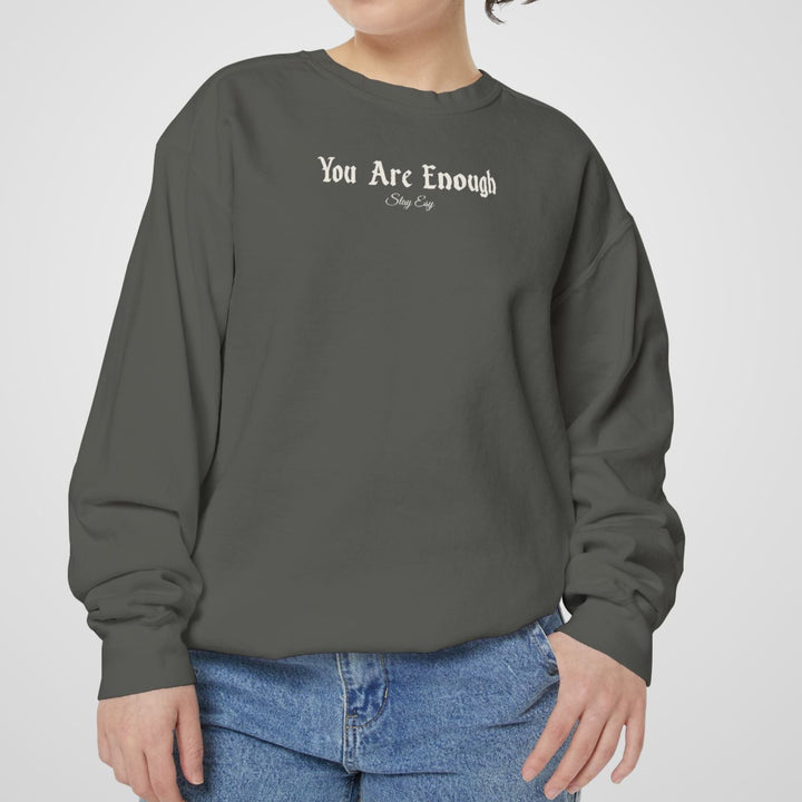 Person wearing a gray sweatshirt with 'You Are Enough' text on a plain background