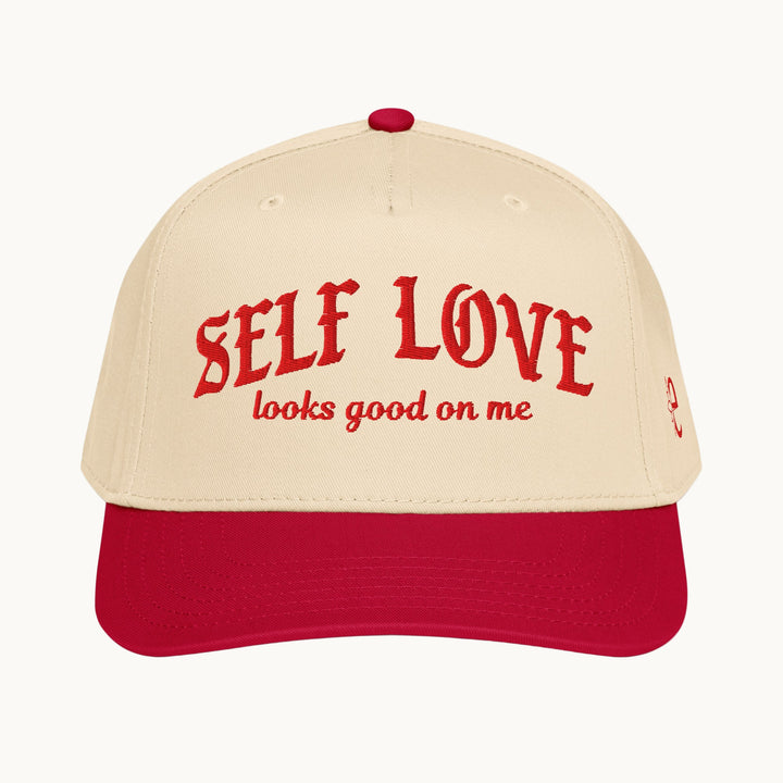Beige and red cap with 'SELF LOVE looks good on me' text on a white background