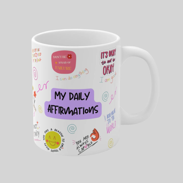 White ceramic mug featuring inspirational daily affirmations, perfect for morning coffee ritual and self-care routine