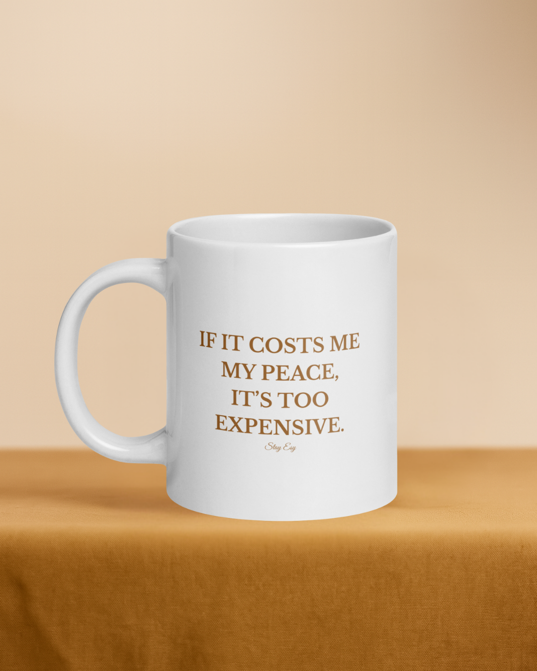 White mug with gold text on a beige background