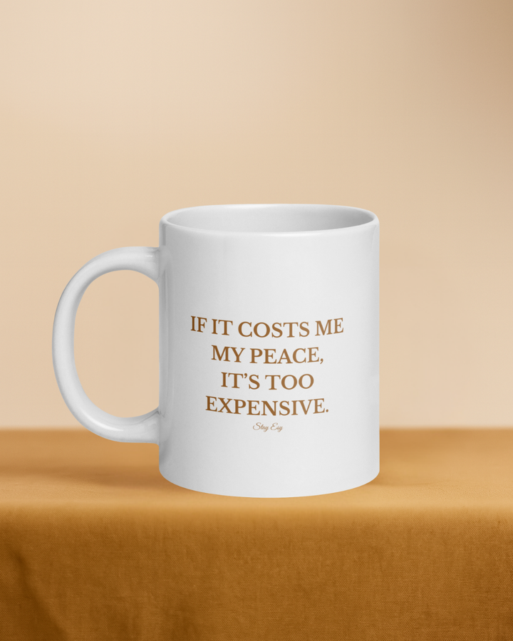 White mug with gold text on a beige background