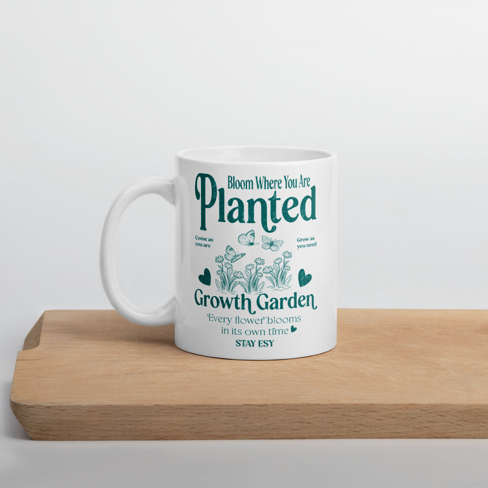 White mug with green text and gardening graphics on a wooden surface