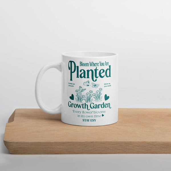 White mug with green text and gardening graphics on a wooden surface