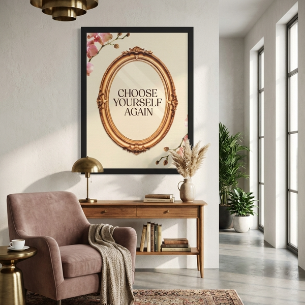 A framed wall art print with the text 'CHOOSE YOURSELF AGAIN' inside an ornate gold oval, displayed above a console table in a styled living room with a pink armchair, lamp, plants, and windows.