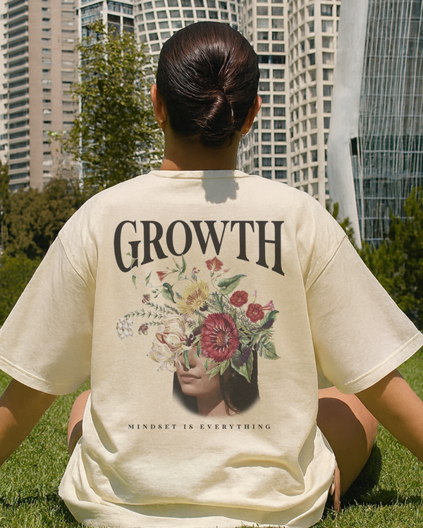 Woman sitting out in the park with a cream faded tee on.
