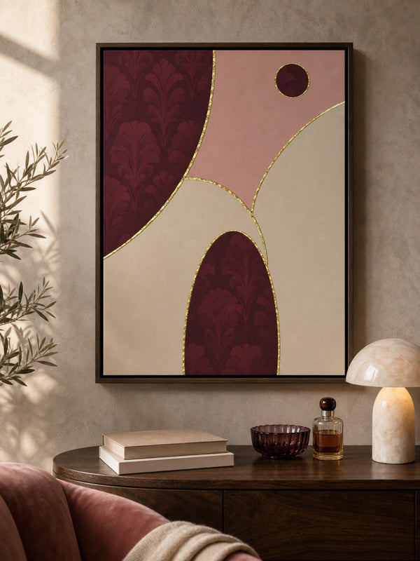 A framed abstract wall art print hangs above a dark wood console table in a styled interior. The artwork features flowing organic shapes in deep burgundy, dusty pink, cream, and thin gold linework.