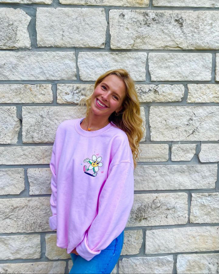 Woman wearing a pink sweatshirt with a design in front of a stone wall