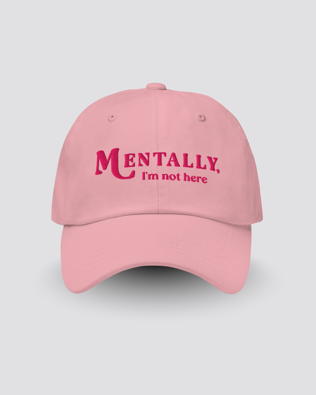 Pink cap with 'MENTALLY, I'm not here' text on a light gray background