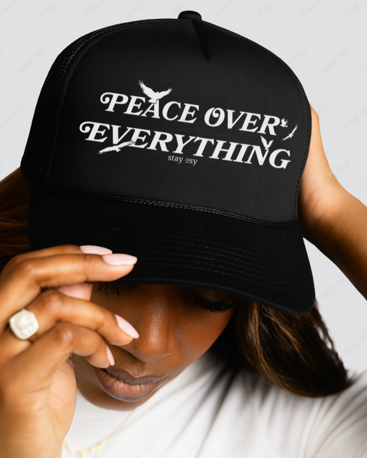 Black cap with 'Peace Over Everything' text worn by a person