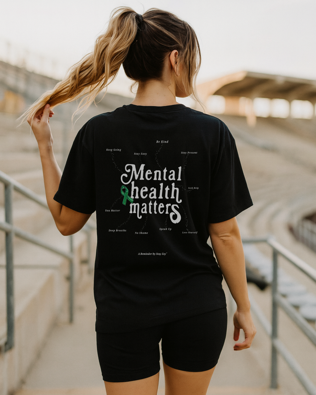 Person wearing a black t-shirt with 'Mental health matters' text and green ribbon graphic.