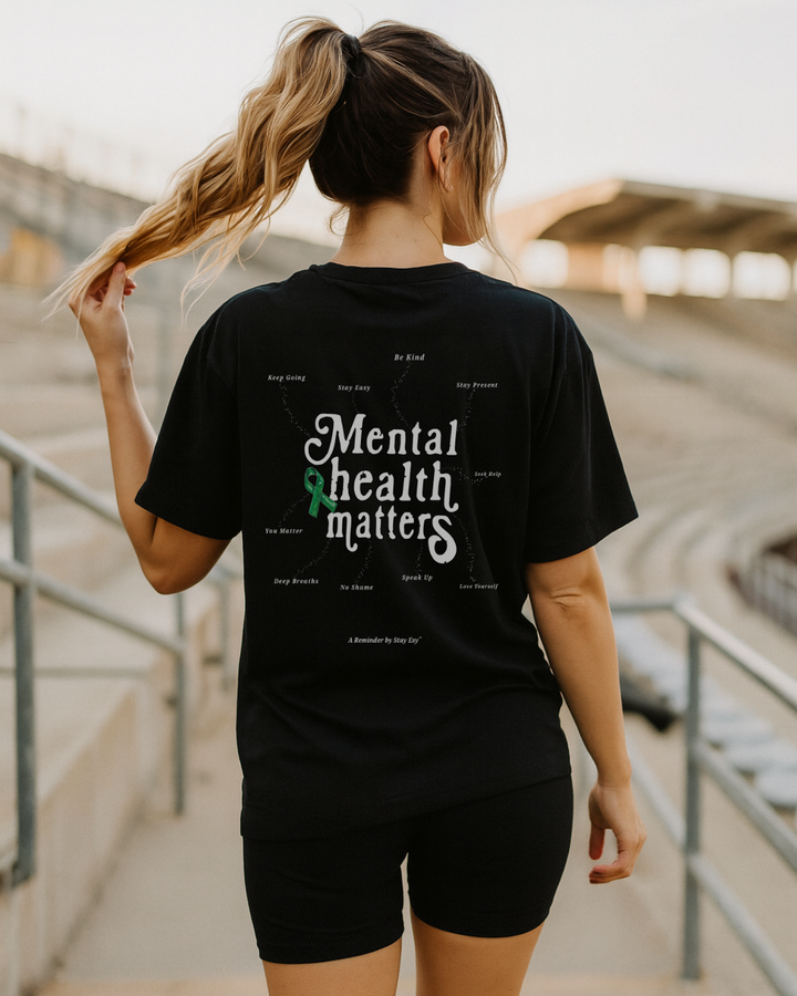 Person wearing a black t-shirt with 'Mental health matters' text and green ribbon graphic.