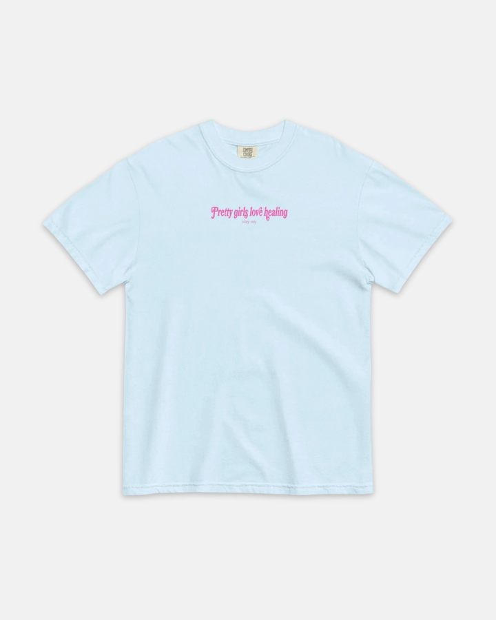 A light blue short-sleeve crewneck t-shirt with pink gothic-style text on the chest reading &