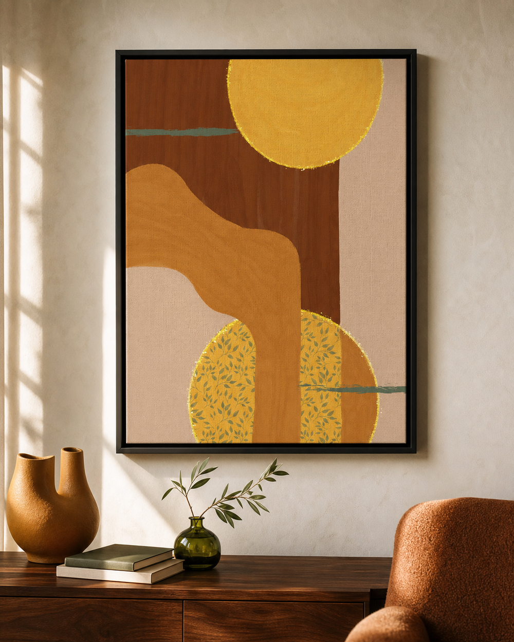 A framed abstract art print with warm earthy tones hangs on a beige wall above a wooden console table. The print features organic shapes in brown, mustard yellow, and cream, with a black frame.