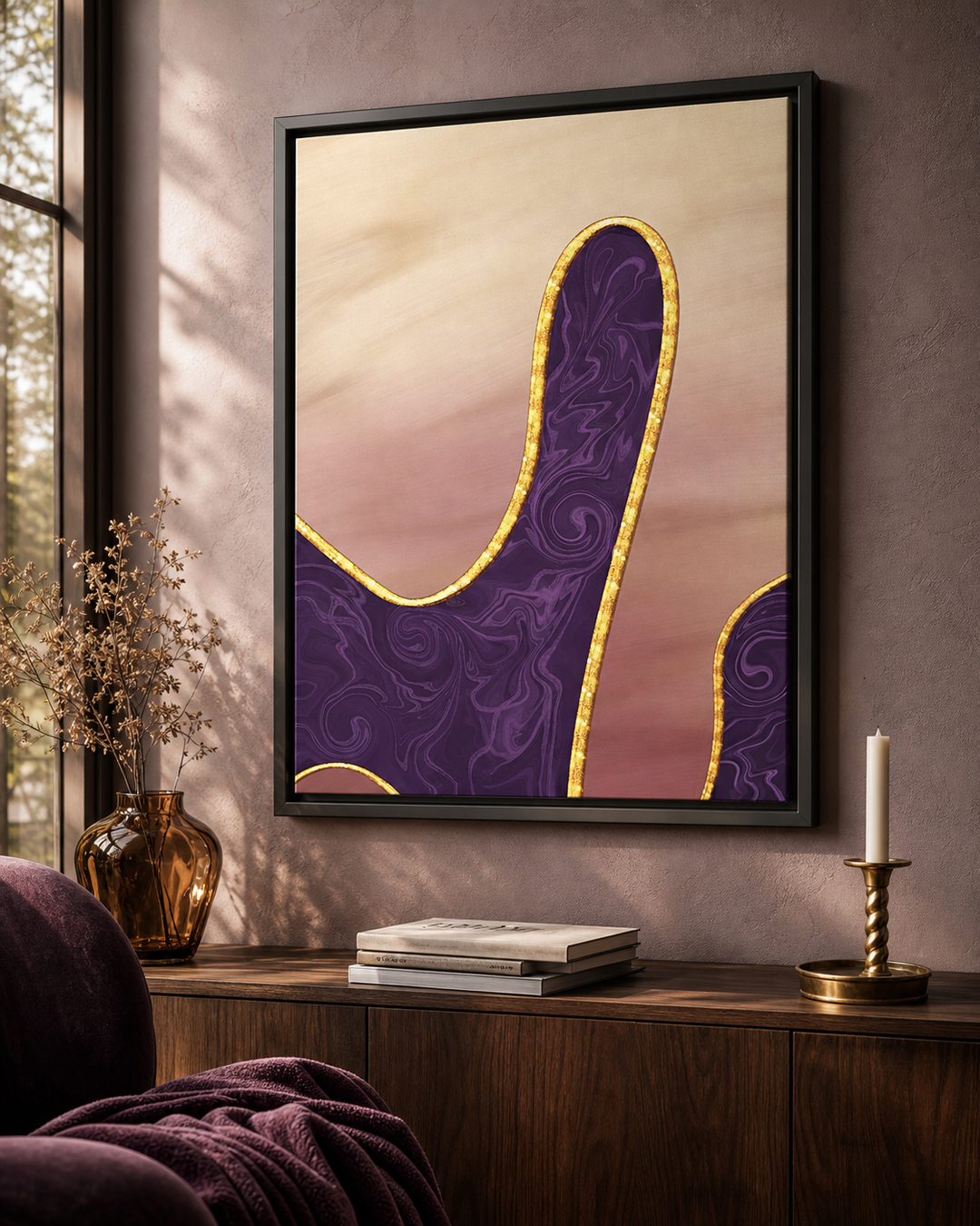 A framed abstract wall art print hangs on a textured taupe wall above a wooden console table. The artwork features a stylized purple shape with swirling patterns and a gold border against a soft beige and pink background.