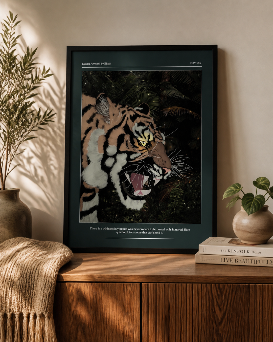 A framed art print featuring a detailed tiger illustration in a jungle scene, styled on a wooden cabinet in a warm, sunlit room with plants and books.