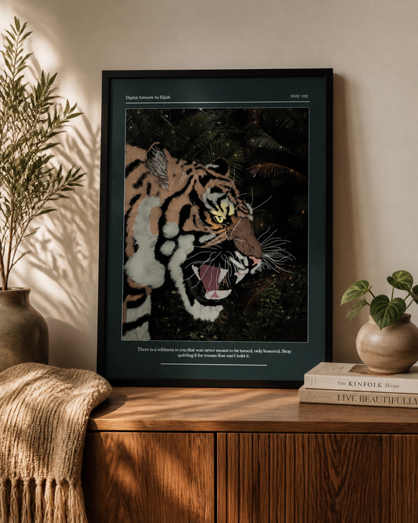 A framed art print featuring a detailed tiger illustration in a jungle scene, styled on a wooden cabinet in a warm, sunlit room with plants and books.