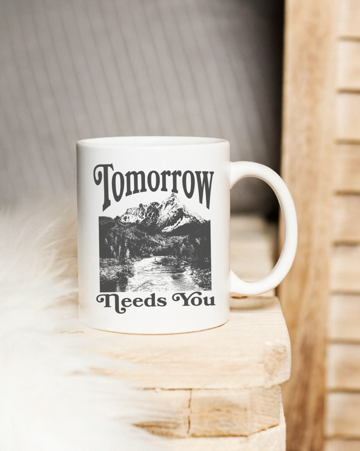 White mug with black text and mountain design on a wooden surface