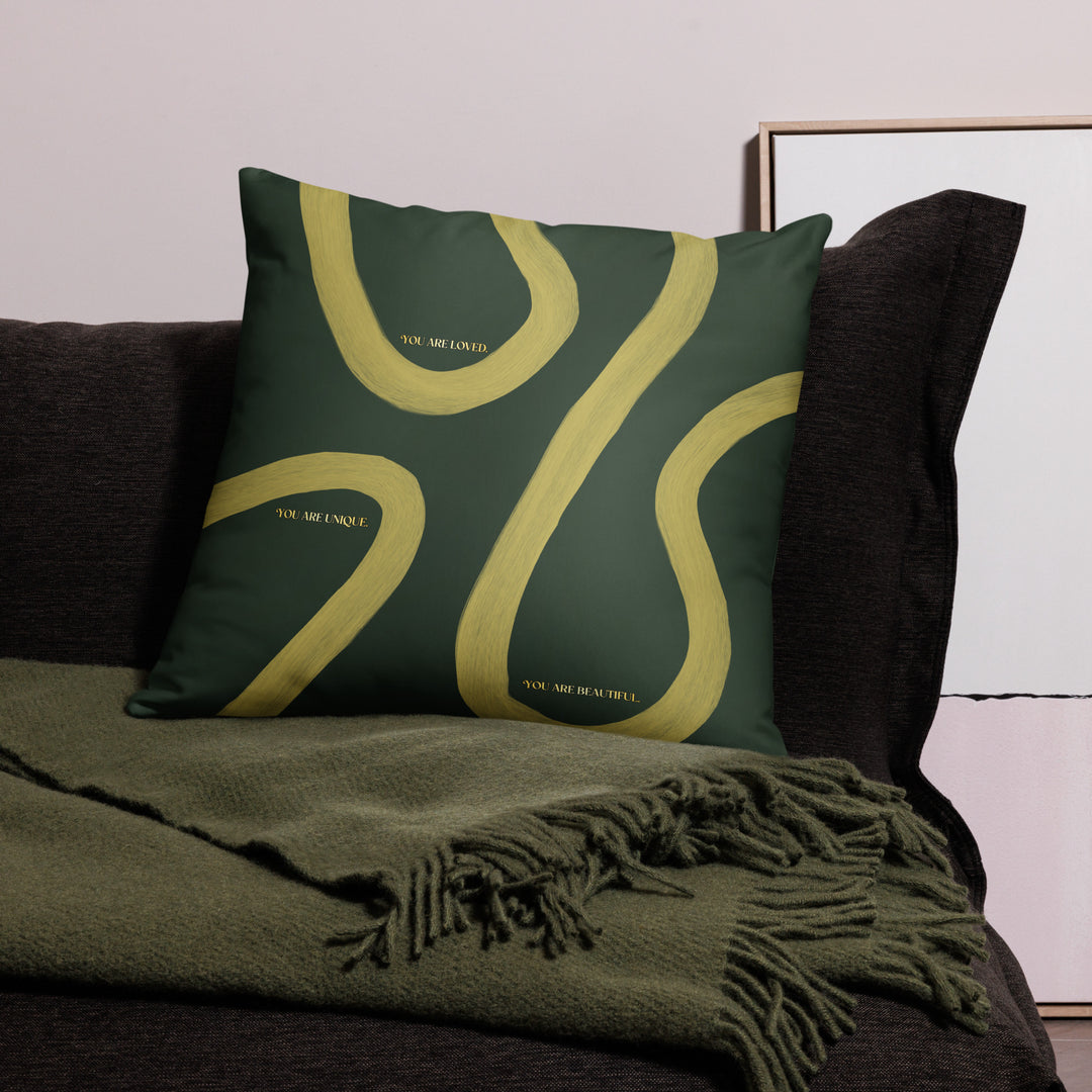 Green pillow with yellow abstract design on a dark sofa with a green blanket.