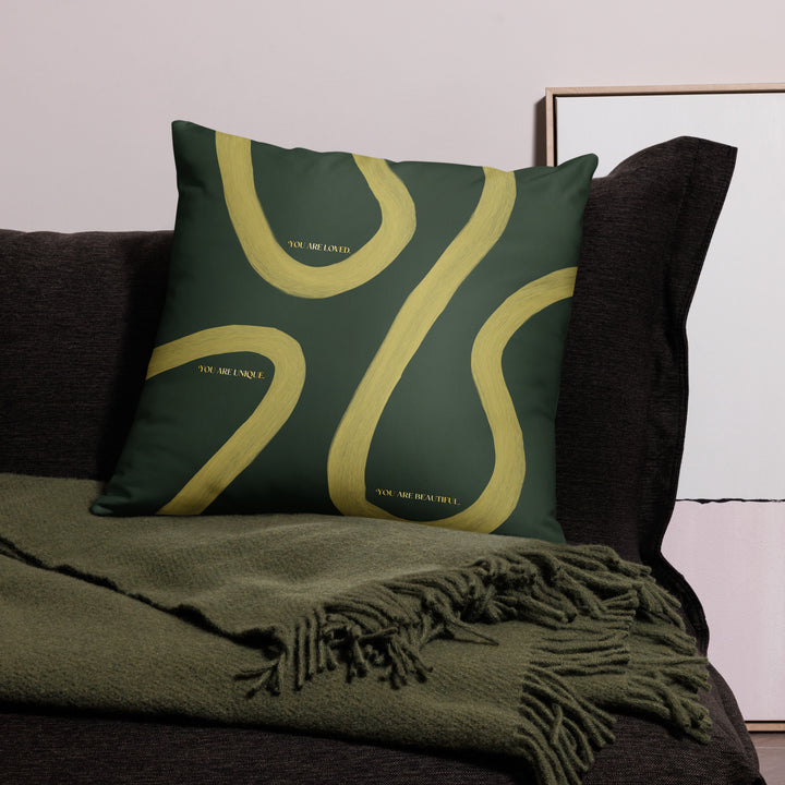 Green pillow with yellow abstract design on a dark sofa with a green blanket.