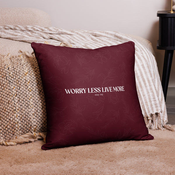 Maroon pillow with 'Worry Less Live More' text on a couch.