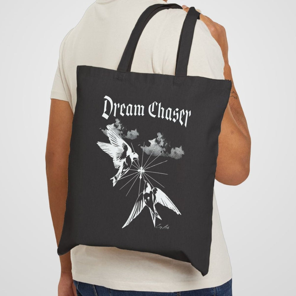 A model carrying the Dream Chaser Black Tote Bag, showcasing its stylish and empowering message for daily inspiration.