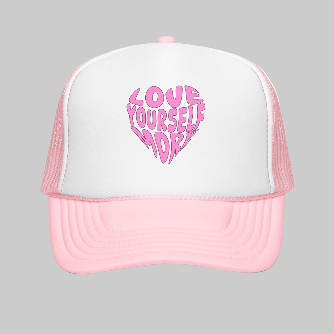 Pink and white trucker hat with 'Love Yourself More' text on a white background