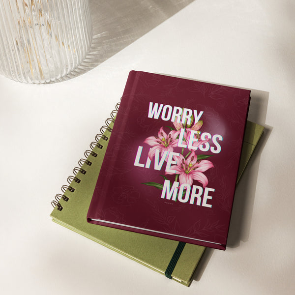 Notebook with 'Worry Less Live More' text and flowers on a white surface