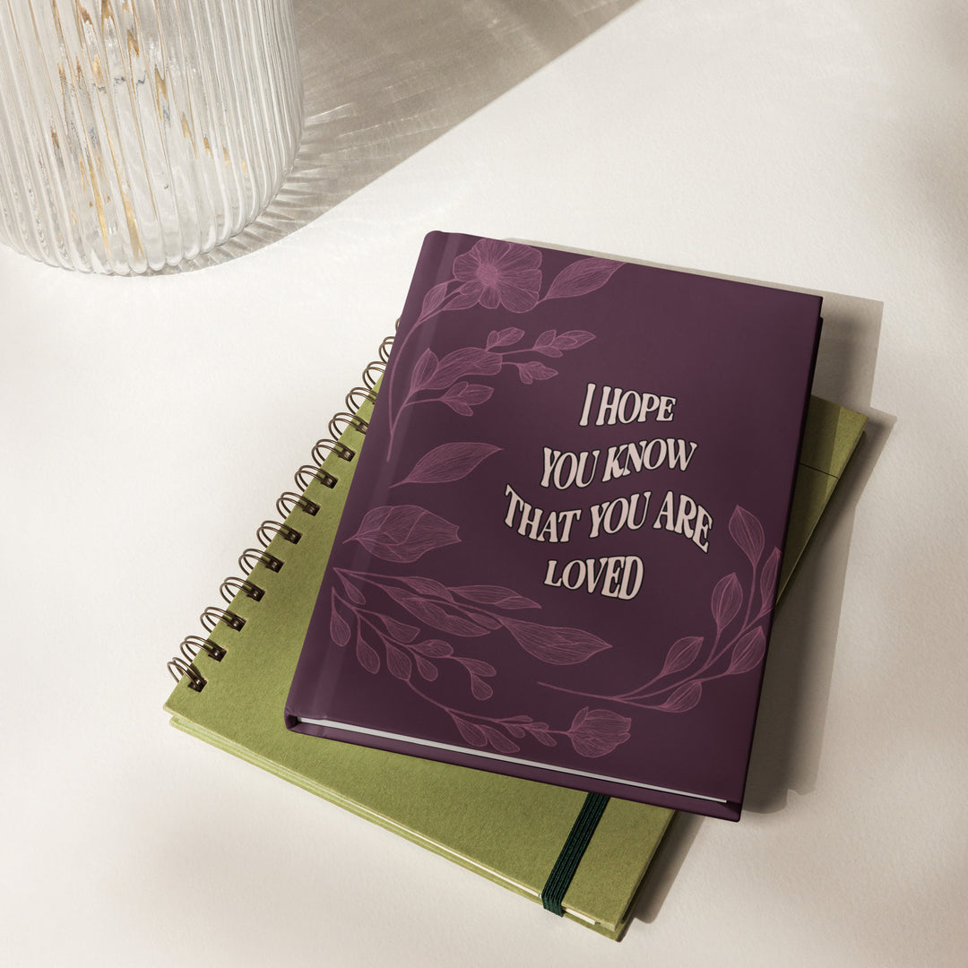 Purple notebook with floral design and text on a white surface