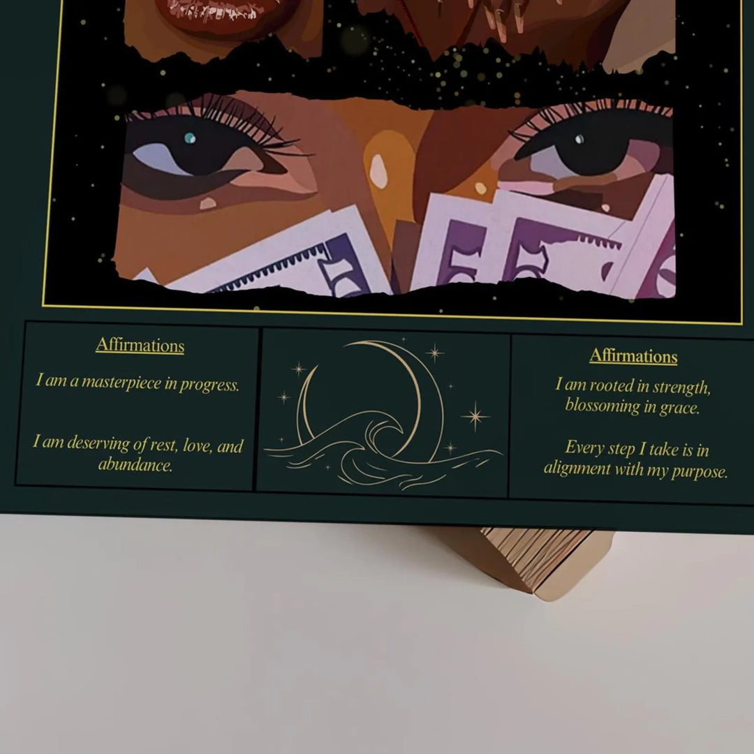 A close-up of a decorative affirmation card or print with illustrated eyes, stars, and text panels reading affirmations, displayed on a small wooden stand against a light neutral background.