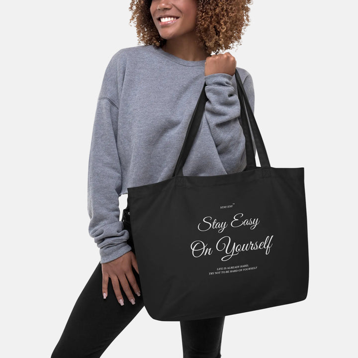 Woman holding a black tote bag with a smiley face design on a white background