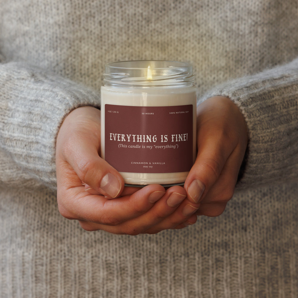 Hand holding a candle labeled 'Everything is Fine!' with a soft background