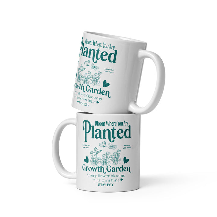 Two white mugs with green text and floral designs on a white background
