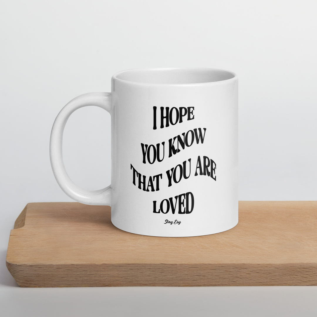 White mug with motivational quote on a wooden surface