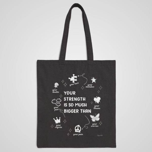The Your Strength Is So Much Bigger Graphic Tote Bag in black, a durable canvas tote promoting mental health awareness and self-empowerment.